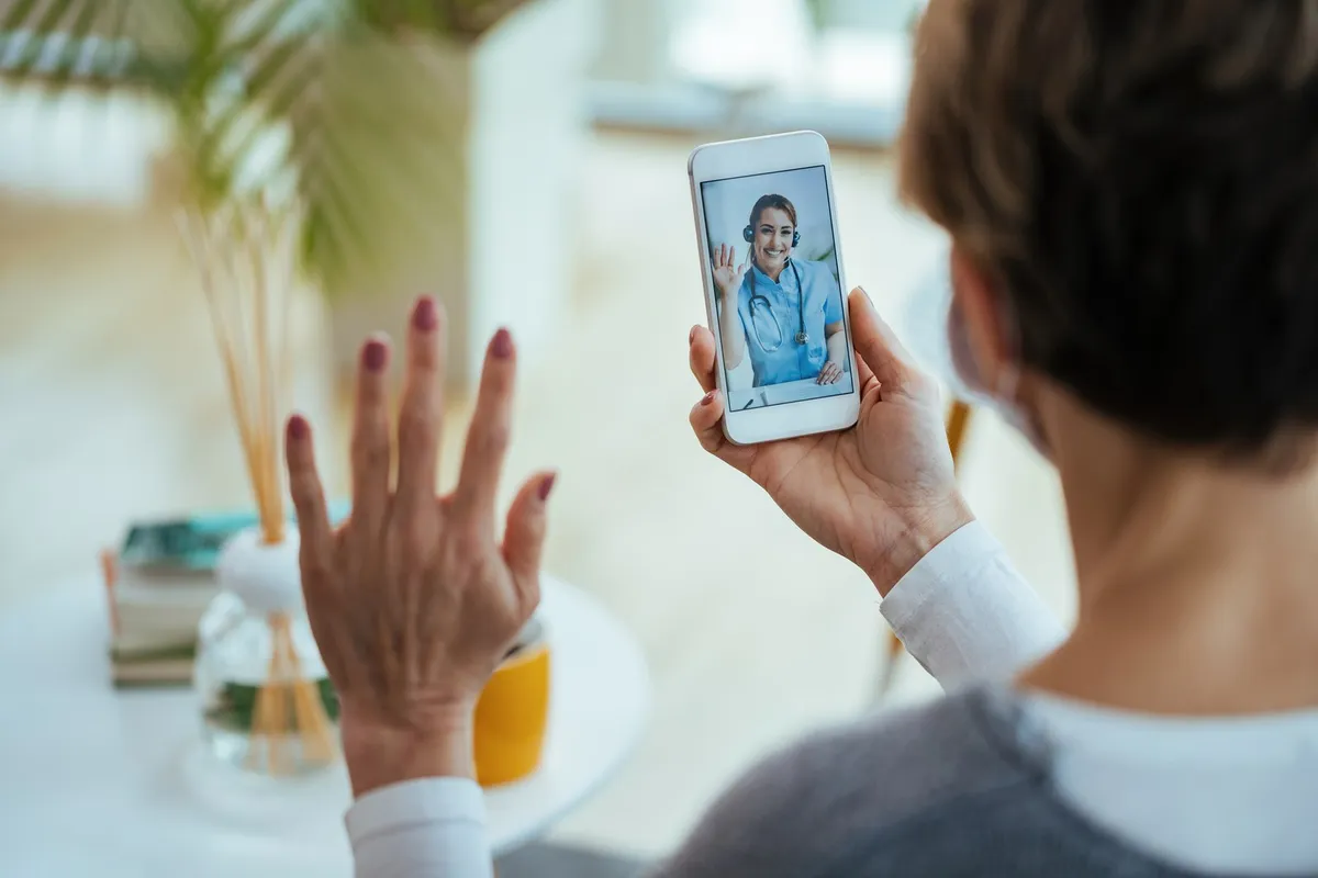 Mulher em consulta por vídeo com a médica pelo celular
